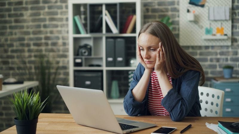Event Planner Sitting At Computer Concerned About Avoiding Speaker Cancellations
